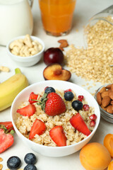 Bowl of oatmeal and ingredients for cooking on white background