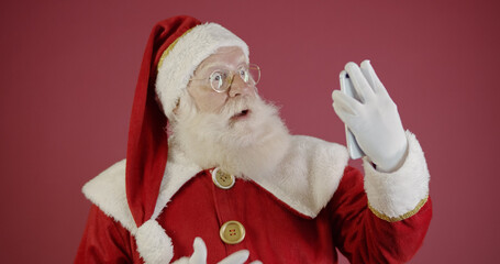 Stylish trendy grandfather aged mature Santa tradition winter costume headwear spectacles white beard take christmastime selfie picture front camera in red background