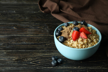 Bowl of oatmeal and kitchen towel on wooden table