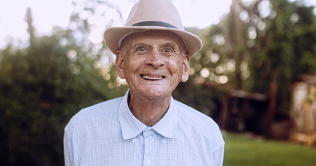 Smiling beautiful older male Latin farmer. Elderly man at farm in summer day. Gardening activity....