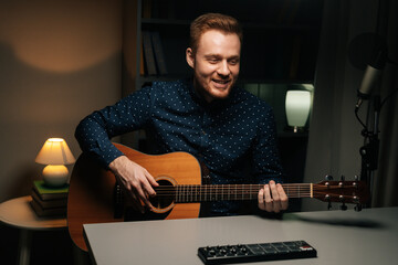 Portrait of guitarist singer man emotionally singing into condenser microphone and playing acoustic...
