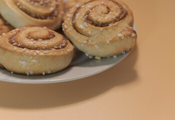Cinnamon rolls on a white plate with an orange - peach background