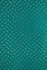 Turquoise fabric background with gold interspersed and gold stitches. Cotton fabric with a simple pattern