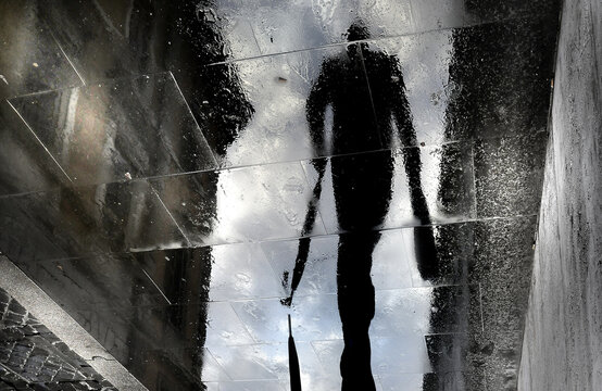 Reflection of a person in the water puddle on a street