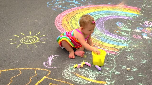 The child draws a rainbow with chalk. Selective focus.