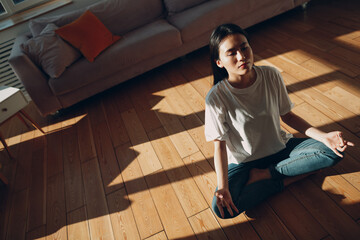 Asian korean or japanese woman doing yoga and zen like meditation lotus pose in casual wear at...