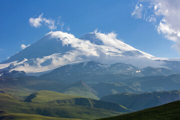 Mountain landscape. The Caucasus Mountains. Elbrus on the background of green hills. Blue sky. A  summer day. Russia.