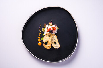 dish with sea bass carpaccio, croutons, cherry tomatoes, capers and mango mousse. White background