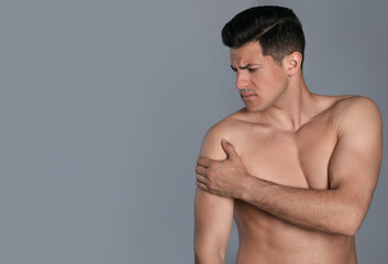 Fototapeta premium Man suffering from shoulder pain on grey background. Space for text