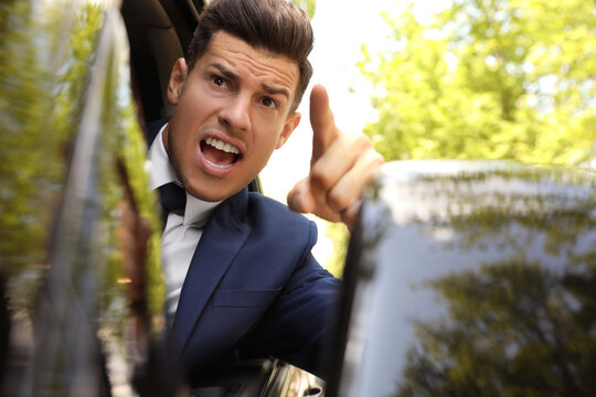 Emotional man yelling in car, view from outside. Aggressive driving behavior