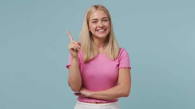 Insighted proactive young blonde woman 20s wears pink t-shirt looks around thinks scratches at temple comes up with ideas raised finger isolated on pastel light blue color background studio portrait
