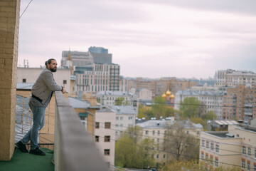 Portrait of a young handsome man on the balcony overlooking the city. City life.