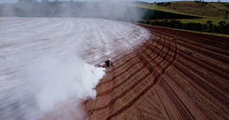 Tractor applying limestone to the soil to correct acidity - obrazy, fototapety, plakaty