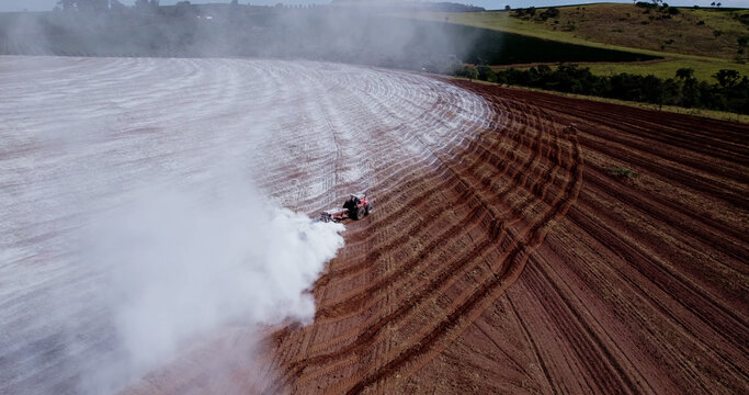 Tractor applying limestone to the soil to correct acidity