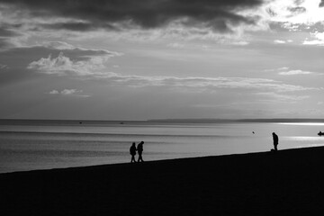 Human silhouettes on the beach, black and white seascape 