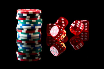 Red casino dice and chips isolated over black reflective background