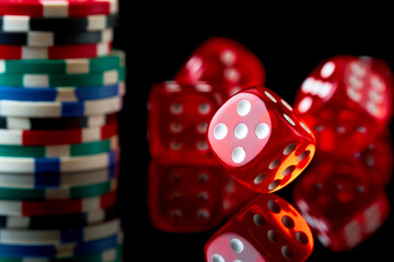 Red casino dice and chips isolated over black reflective background