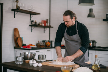 A male chef prepares dough at home in the kitchen