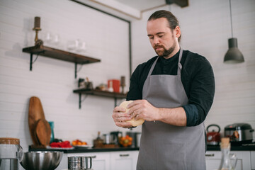 A male chef prepares dough at home in the kitchen