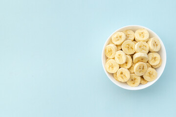 Many banana slices in white bowl. Top view