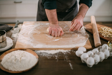 A male chef prepares noodles at home in the kitchen.