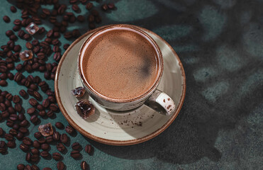 Fragrant strong coffee and coffee beans on a dark green concrete background. The concept of hot drinks.