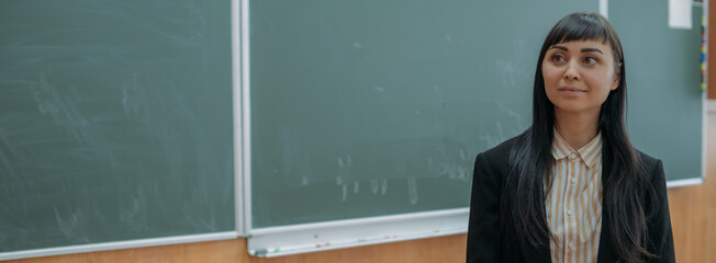 Portrait of a young teacher at the blackboard at school