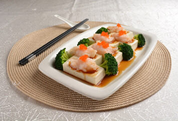 steamed bean curd tofu with minced prawn seafood on top and broccoli vegetables in dark soy sauce on white background Asia appetiser halal menu