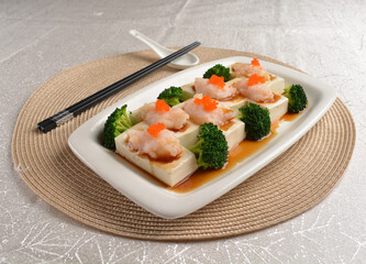 steamed bean curd tofu with minced prawn seafood on top and broccoli vegetables in dark soy sauce on white background Asia appetiser halal menu
