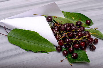 white paper bag with cherries and foliage on a painted wooden surface