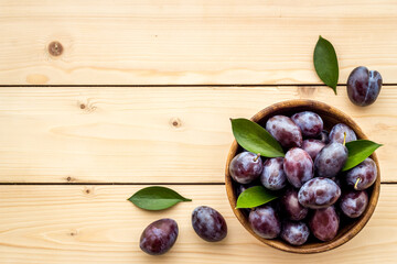 Food layout with plums in bowl with leaves. Top view