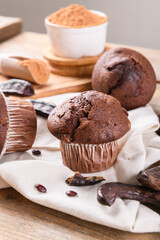 Chocolate carob cupcakes cooking with carob powder and dried carob pods and carob powder in a bowl over wooden background. Organic healthy sweet food for vegan vegetarian food and drinks, close up