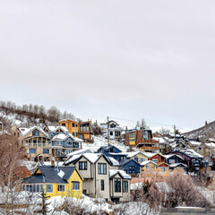 Fototapeta na wymiar Square Mountain town on a cloudy winter landscape with homes on snowy slope terrain