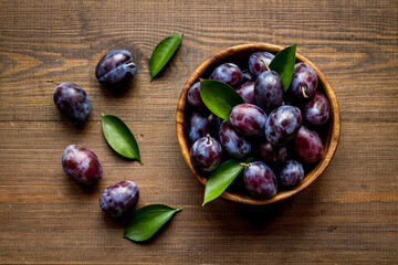 Ripe garden plums in bowl. Cherry fruit with leaves. Top view
