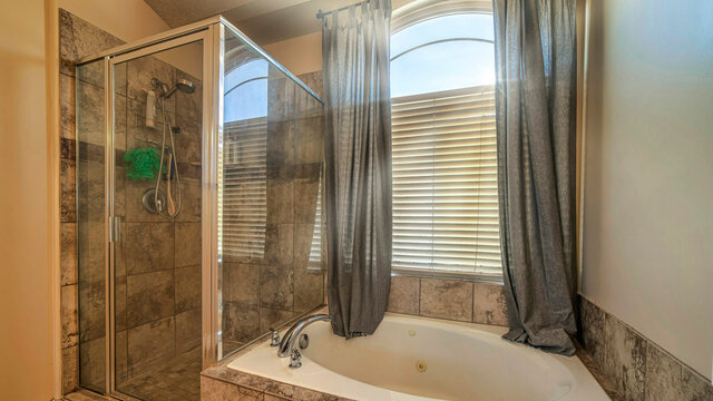 Pano Bathroom interior with round built in bathtub shower stall and warm toned tiles