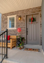 Vertical Outdoor stairs leading to porch and gray front door with wreath and glass pane