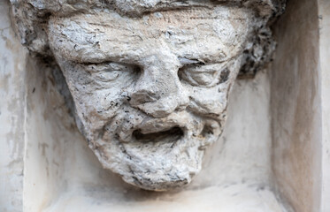Trento, Italy, June 2021. Ancient bas-relief of a face in stone on the facade of a house. Time has...