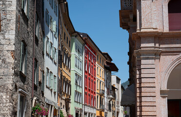 Fototapeta na wymiar Trento, Italy, June 2021. Beautiful view of one of the streets of the historic center characterized by brightly colored facades. Beautiful summer day.