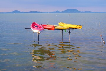 vibrant color kayaks on the pier with reflection in the water of the lake Balaton in Hungary in...