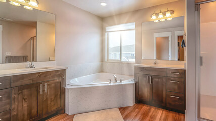Fototapeta na wymiar Pano Beautiful home bathroom with built in corner bathtub between two vanity units