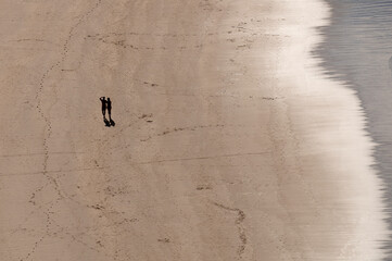 A silhouette of a couple walking alone during a summer day in Torimbia Beach, Asturias, Spain.