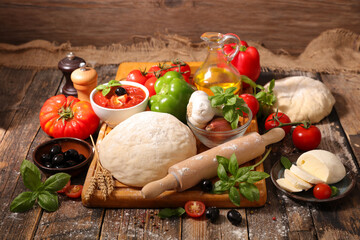 raw dough pizza with ingredient on wood background