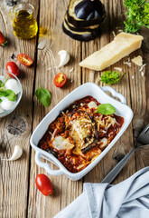 Parmigiana is Italian traditional dish with main ingredients in rustic style. Flat lay, vertical banner