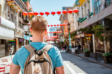 Rear view of a young man walking through Chinatown in downtown San Francisco. San Francisco, USA -...
