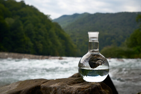 Bottle of drinking water on the shore of a mountain river.