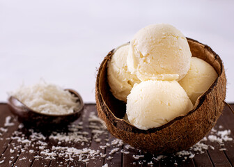 Coconut ice cream in natural coconut shell with grated coconut decoration in the background