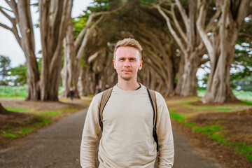Dramatic landscape and a young man in the Cypress Tree Tunnel near San Francisco, USA
