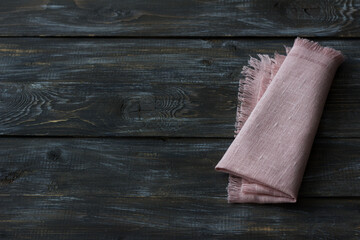 Pink linen napkin with fringe on a wooden background, flat lay, space