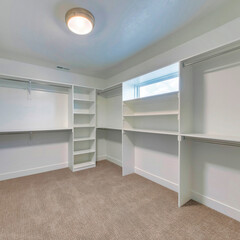 Square frame Walk in closet of house with empty built in shelves and two levels clothing rods