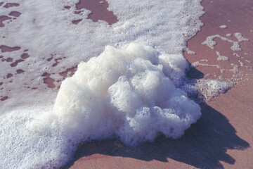 Image of sea foam on a sandy beach.